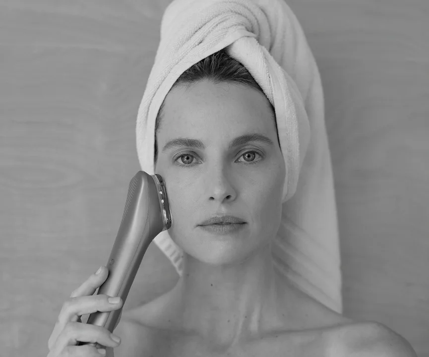 Black-and-white portrait of a woman holding a device beside her cheek