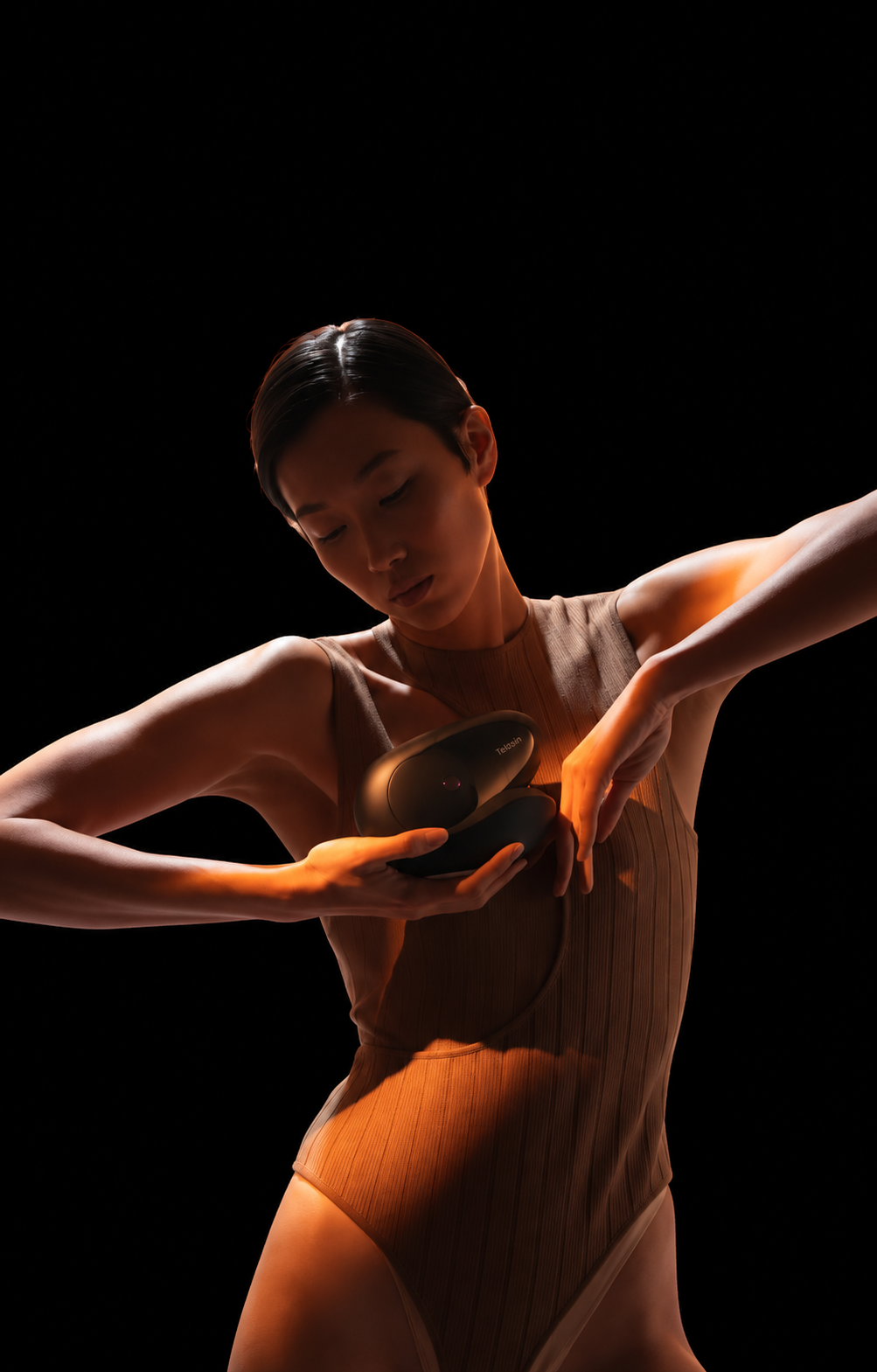 Model holding a Telosin Body Sculpt device beside her upper arm